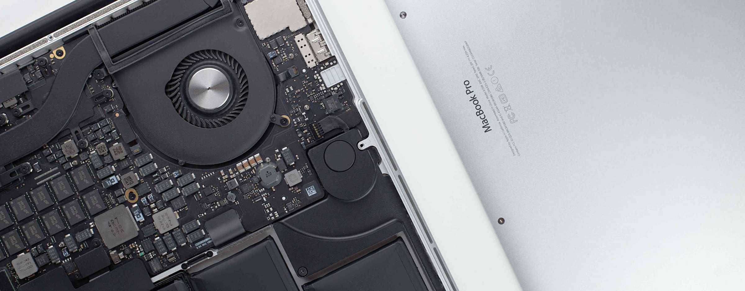 A MacBook Pro with the backcase off showing the internal circuits and fan.